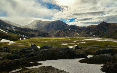 Sunlight breaks through clouds over a winding river valley