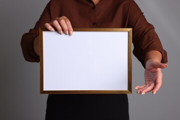 Naklejka premium Woman with blank diploma frame on light grey background, closeup. Mockup for design