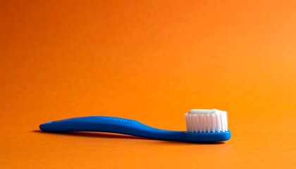 Blue toothbrush with white bristles lies on an orange background