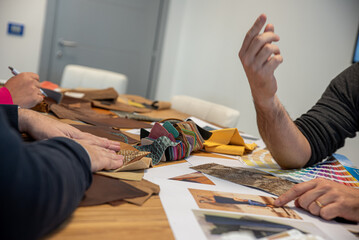 Designers collaborate on fabric selection for a fashion collection in a bright studio space with colorful materials