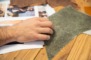 Obraz premium Hand touching textured fabric samples during a design project in a creative workspace