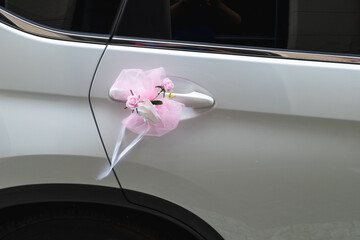 Pink and white floral decor on car handle symbolizes celebration