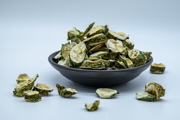 흰색배경 앞 검은색 그릇에 담긴 말린 여주 