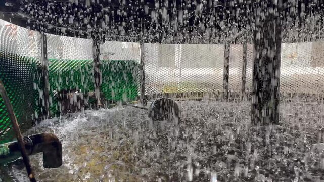 Water splashing inside an industrial cooling tower's louver or mesh intake during operation. Essential HVAC cooling system for large-scale buildings or factory plant.