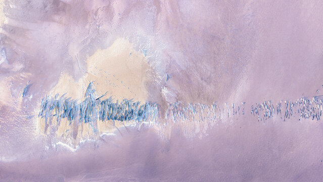 Aerial drone view of a weathered salt-crusted stick walkway crossing a dry pastel Australian salt pan near Lake Tyrrell, Mallee, Victoria, Australia