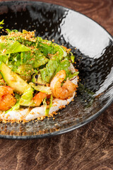 Gourmet salad with cucumbers, orange slices, greens, seeds, and creamy dressing on a dark ceramic plate. Rustic wooden background. Fresh, vibrant, and artfully plated.