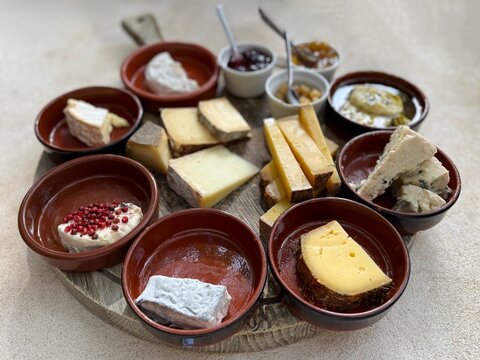 Close-up of a round cheese board with assorted hard and soft cheese, jams and chutneys