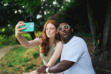 Young couple taking selfie and making funny faces outdoors