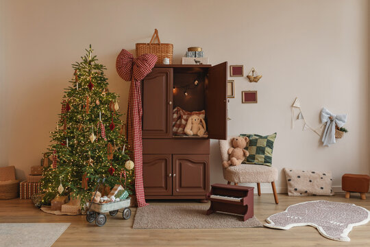 Illuminated Christmas tree next to a cupboard and wagon with wrapped Christmas gifts in children's room