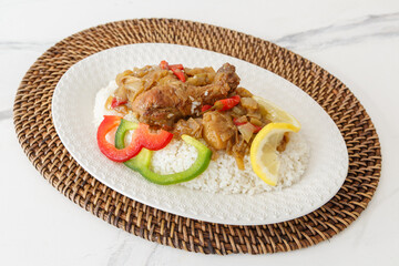 Poulet Yassa – plat traditionnel sénégalais aux oignons et citron, présenté sur un dessous de plat africain tissé. Plat emblématique du Sénégal et de la cuisine d’Afrique de l’Ouest.
