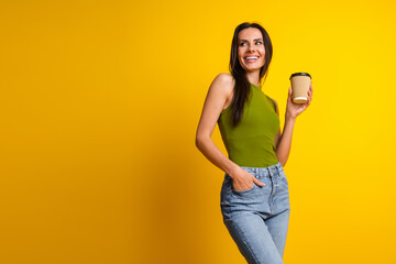 Attractive young woman in casual fashion holding a coffee cup against vibrant yellow background