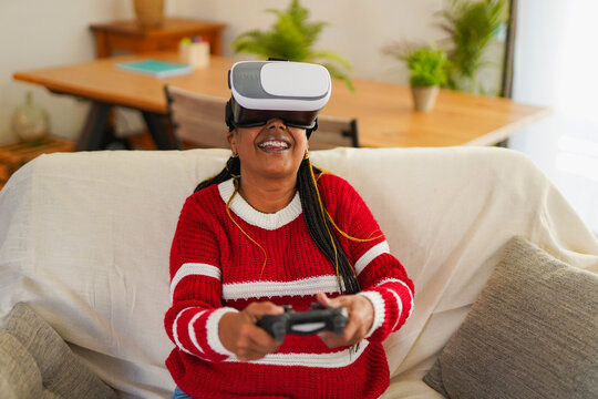 Happy senior african woman play video games using virtual reality headset at home - Lifestyle, elderly person and technology concept