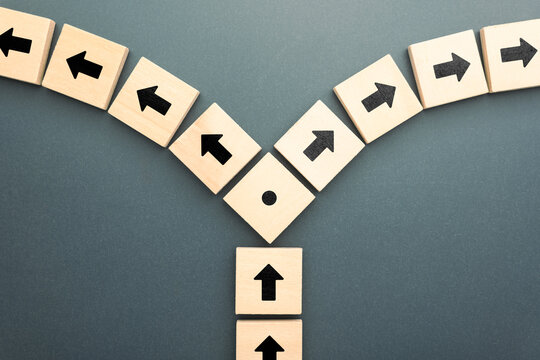 Wooden blocks with arrows pointing in opposite directions symbolizing conflict of interest disagreement or divided decision in relationships business or ethics