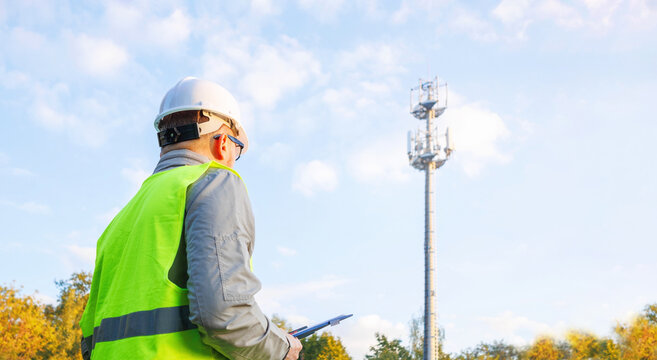 Male engineer inspector maintains a telecommunications tower. Inspecting 4G and 5G network equipment. Maintenance of cellular communication poles. 