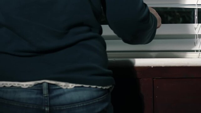 Hand opening window blinds nervously