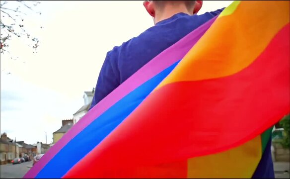 Un chico mostrando la bandera del arcoiris con orgullo