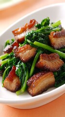 Stir-fried crispy pork belly with Chinese kale, glossy sauce, elegant white plate, soft warm peach background, shallow depth of field.
