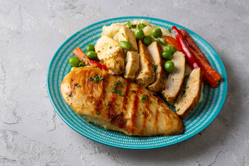 Grilled chicken breast slices served with mashed potatoes and vegetables.