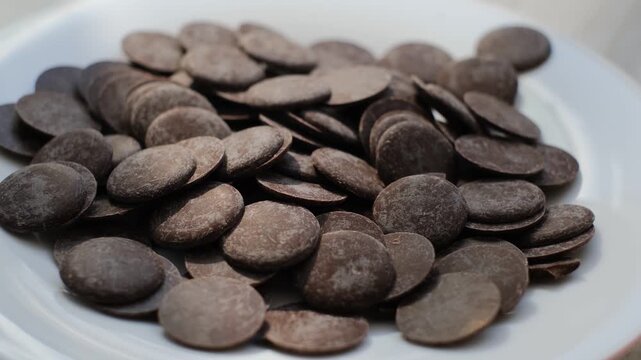 Hardened round pieces of dark chocolate on a plate