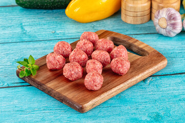 Raw beef meatballs over board