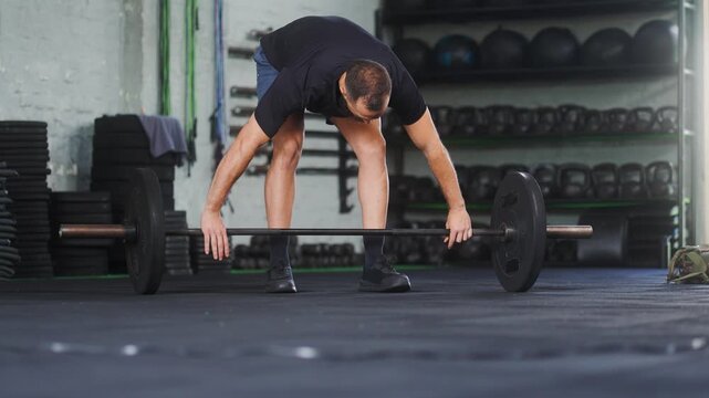 Mid adult athletic man with beard performing barbell snatch exercise