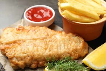 British Traditional Fish and chips served with sauce on grey table, closeup