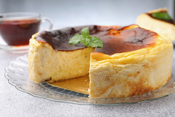 Delicious Basque cheesecake with mint and tea on light grey table, closeup