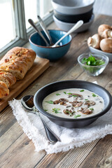 A bowl of homemade cream of mushroom soup served with crusty bread.