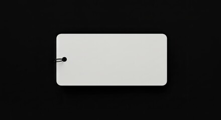 A white rectangular tag with rounded corners is centered on a solid black surface attached with a black ring