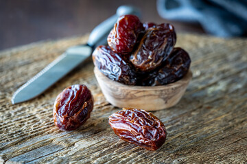A small bowl of medjool dates with two whole dates in front.