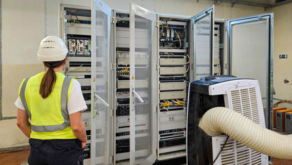 Female engineer checking control racks and network equipment in industrial automation system room