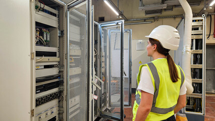 Female engineer checking control racks and network equipment in industrial automation system room