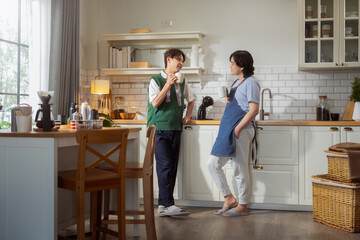 Asian mature man enjoys morning coffee at cafe using drip coffee bag in beige cup on white wood table, while young adult friends relax making specialty coffee as hobby activity at home	