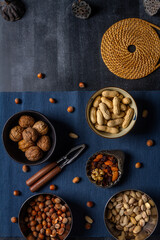 Bowls with nuts and blue table cloth on black chalkboard background. Flat lay. Top view.
