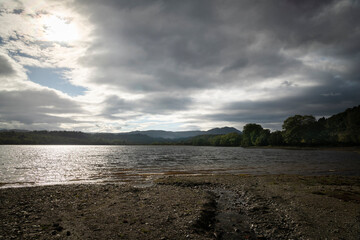A gloomy dark HDR landscape image looking across Loch Vernachar with a burn leading you in, Stirling district of Scotland.