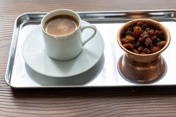 Close-Up of Traditional Turkish Coffee in a White Cup on a Metal Tray with Dried Grapes in a Copper Dish
