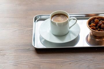 Close-Up of Traditional Turkish Coffee in a White Cup on a Metal Tray with Dried Grapes in a Copper Dish
