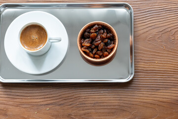 Close-Up of Traditional Turkish Coffee in a White Cup on a Metal Tray with Dried Grapes in a Copper Dish
