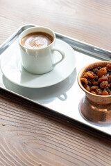 Close-Up of Traditional Turkish Coffee in a White Cup on a Metal Tray with Dried Grapes in a Copper Dish

