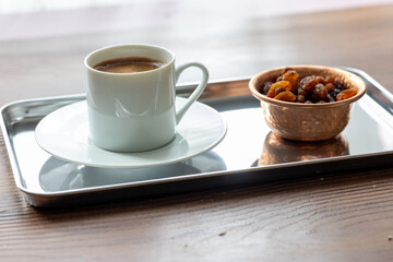 Close-Up of Traditional Turkish Coffee in a White Cup on a Metal Tray with Dried Grapes in a Copper Dish
