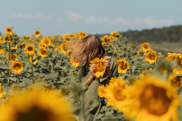 A girl in a pink skirt and a white T-shirt walks through a field of blooming yellow sunflowers. A woman dances, rejoices, smiles, enjoys life, warmth, summer, the sun. High quality FullHD footage