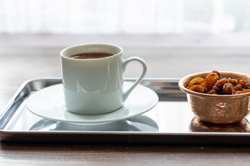 Close-Up of Traditional Turkish Coffee in a White Cup on a Metal Tray with Dried Grapes in a Copper Dish
