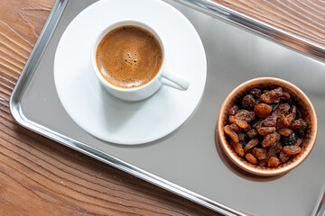Close-Up of Traditional Turkish Coffee in a White Cup on a Metal Tray with Dried Grapes in a Copper Dish

