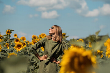A girl in a pink skirt and a white T-shirt walks through a field of blooming yellow sunflowers. A woman dances, rejoices, smiles, enjoys life, warmth, summer, the sun. High quality FullHD footage