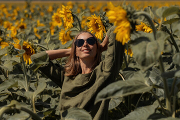 A girl in a pink skirt and a white T-shirt walks through a field of blooming yellow sunflowers. A woman dances, rejoices, smiles, enjoys life, warmth, summer, the sun. High quality FullHD footage