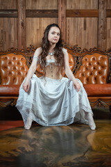 Beautiful sensual woman wears vintage underwear sitting on the brown leather sofa