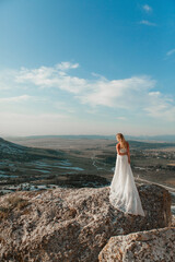a woman in a white dress, a bride on a mountain with a blue sky. Beautiful nature, freedom, enjoyment of life. High quality photo