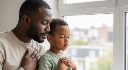 Black father and son praying together with eyes closed. African American family practicing mindfulness and gratitude. Fatherhood and spirituality concept