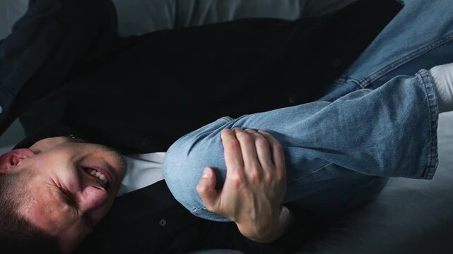 A man massages his sore knee with his hands on a gray sofa.
The man suffers from severe pain due to arthritis.
The man has arthritis of the kneecap.
Pain, health, arthritis, meniscus