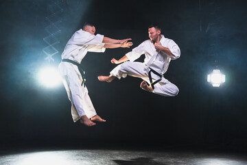 Martial arts masters on dark background. Strong man fighters in white kimono for karate martial...